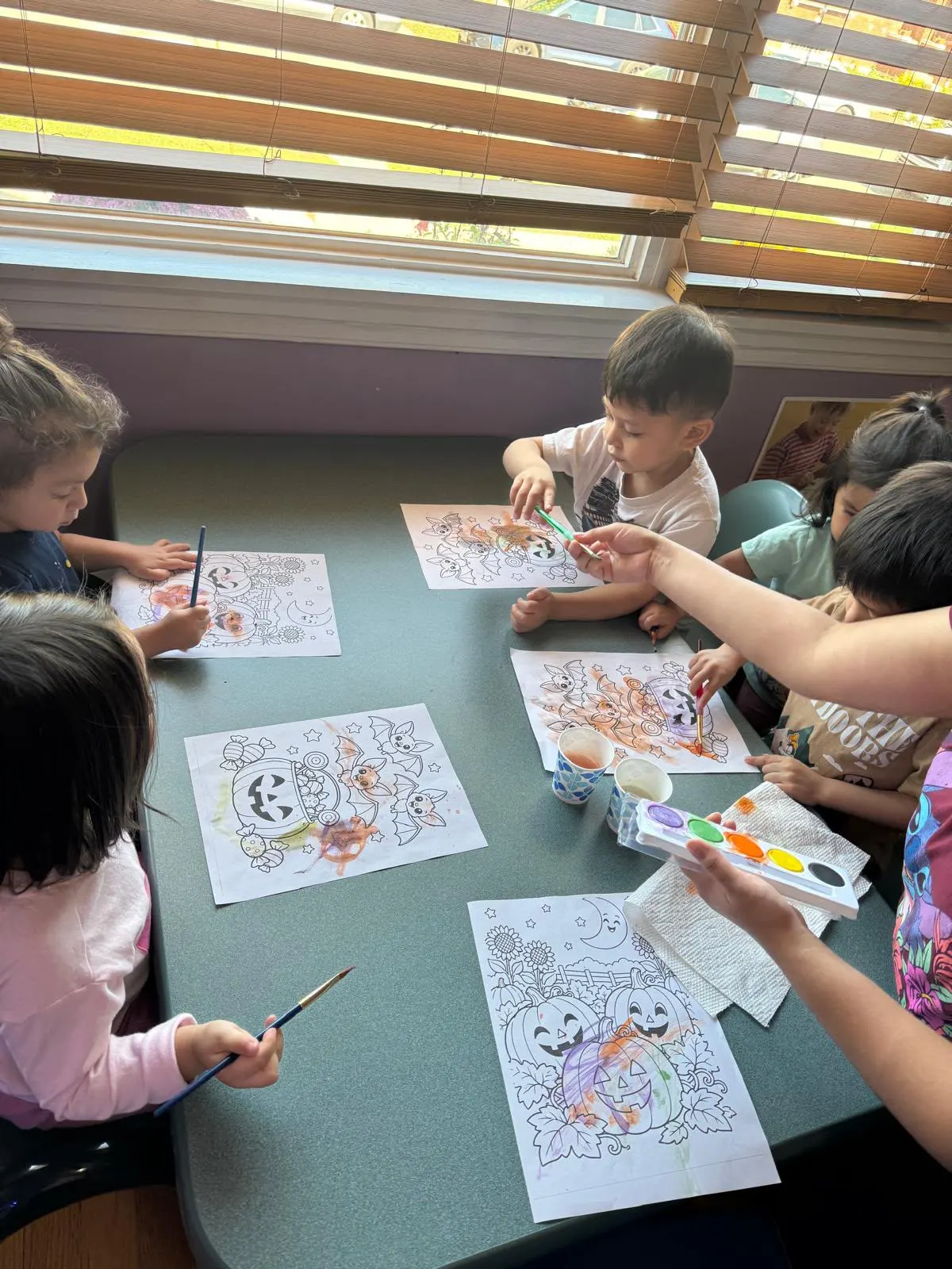 Children painting Halloween coloring pages with watercolors at Liz Daycare