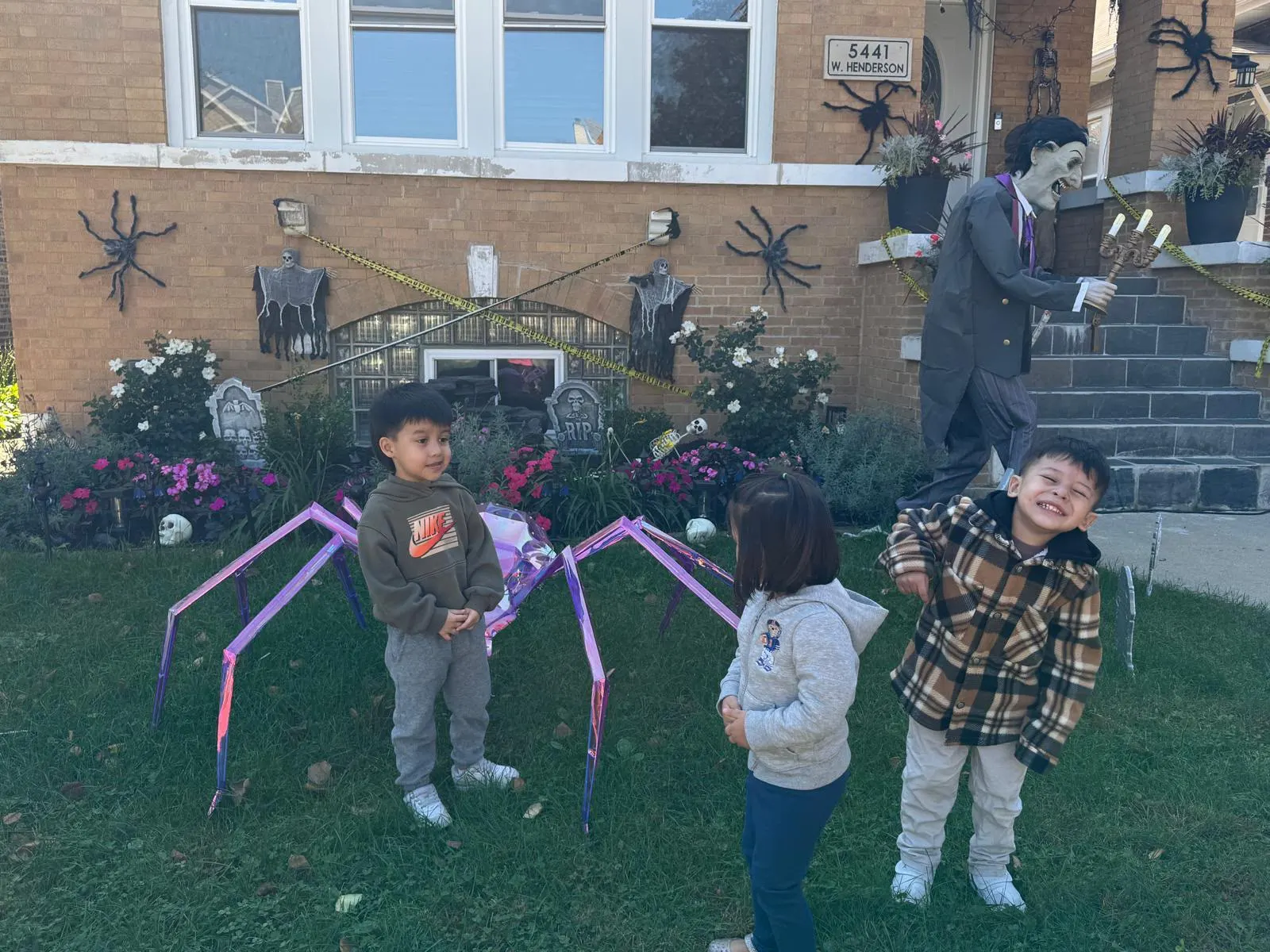 Niños junto a una decoración de una araña morada en la exposición de Halloween de la guardería Liz